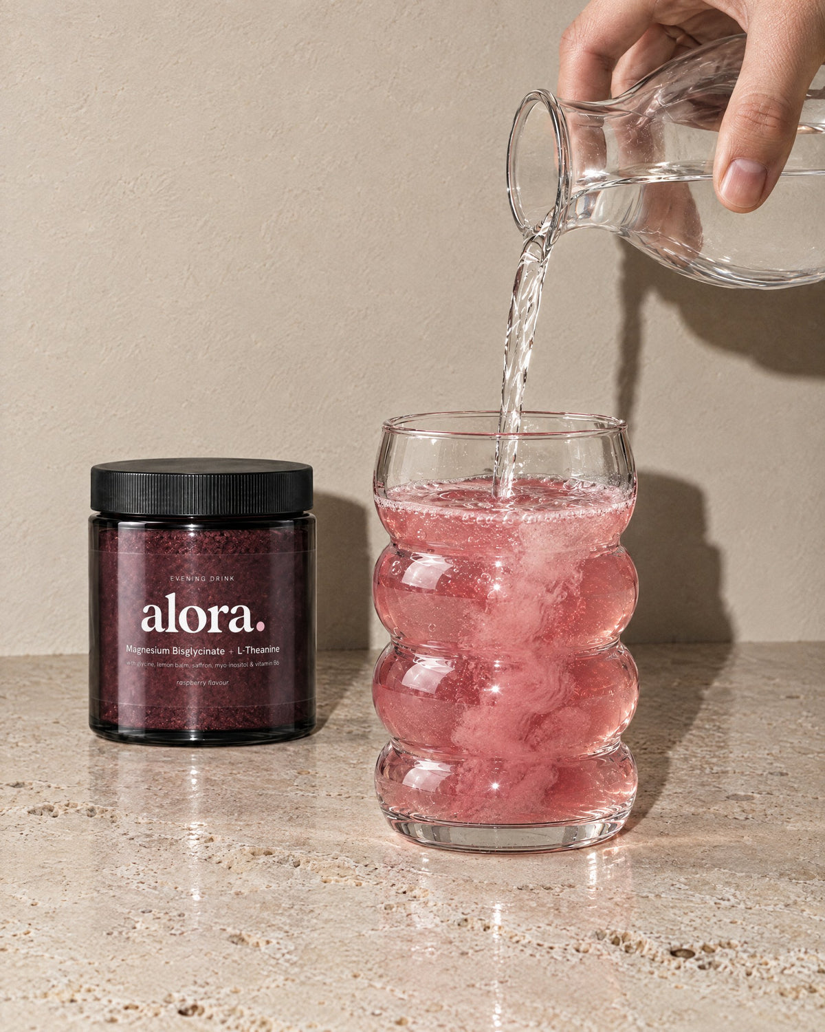 Water poured into a glass of ALORA, the jar beside it (illustrative image)